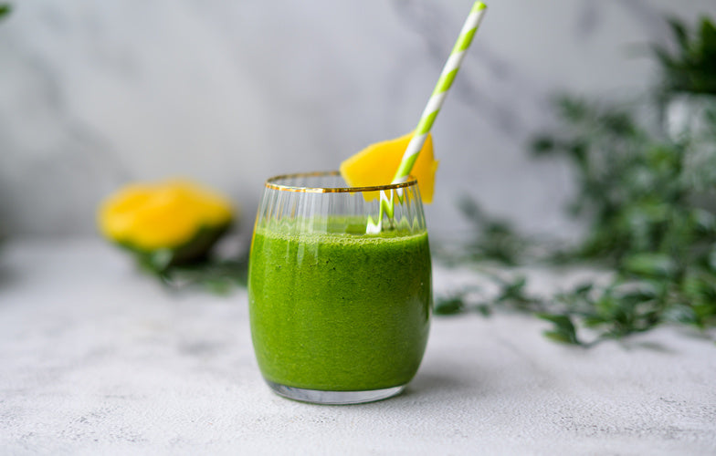 Bleekselderij mango smoothie met spinazie in een glas, gegarneerd met limoen